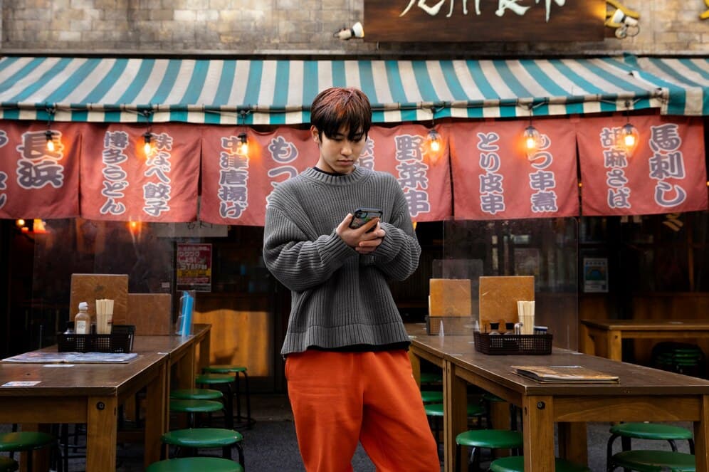 Man Using Smartphone for Digital Payment Outside a Trendy Restaurant